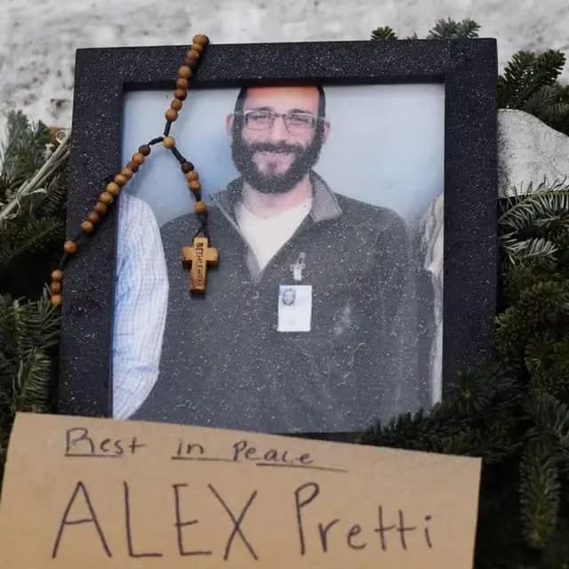 A framed photo of Alex Pretti, a man with a beard and glasses, adorned with wooden rosary beads. Below the frame, a handwritten note on cardboard reads, "Rest in Peace ALEX Pretti."