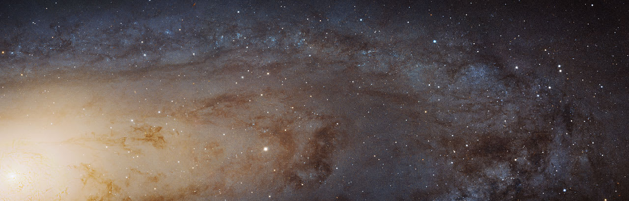 Close-up astronomical photograph showing part of the Andromeda Galaxy, with a bright core transitioning to darker outer regions filled with scattered stars and cosmic dust against a deep space background.