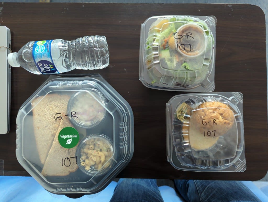 Sample lunch: a sandwich, salad, and roll in plastic packaging, plus a bottle of water.